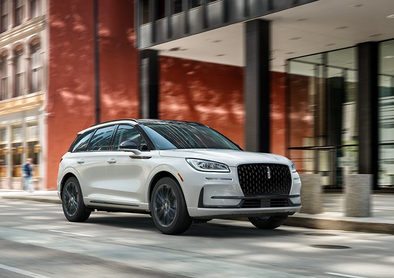 The 2024 Lincoln Corsair® SUV with the Jet Appearance Package and a Pristine White exterior is parked on a city street. | Biondi Lincoln in Monroeville PA