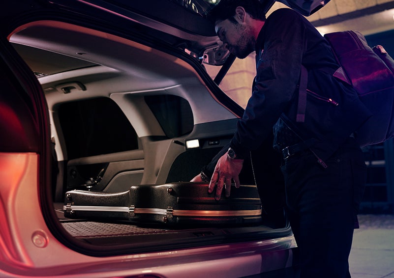 A man is shown loading cargo into the rear of a 2024 Lincoln Corsair® SUV with the second-row seats folded flat. | Biondi Lincoln in Monroeville PA