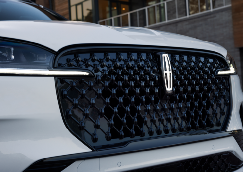 The black grille of a white 2025 Lincoln Aviator® SUV is shown with its fog lights on. | Biondi Lincoln in Monroeville PA