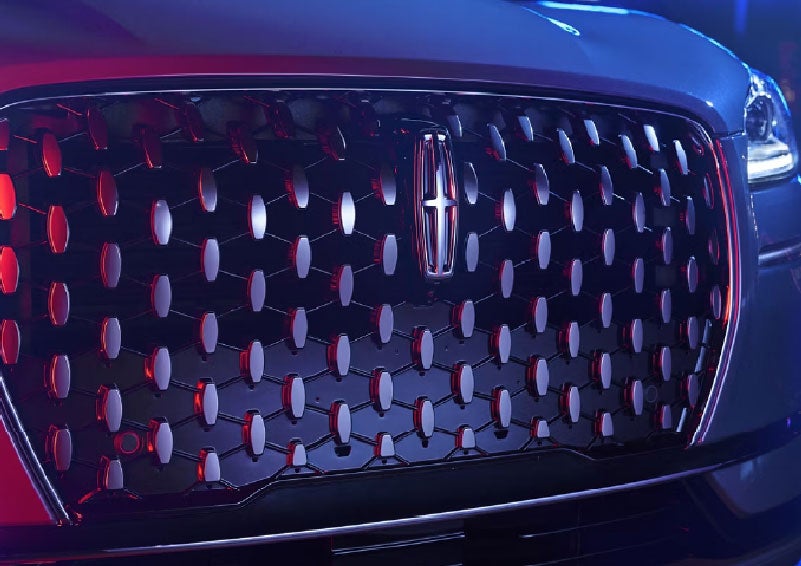 The grille of a 2025 Lincoln Corsair® SUV reflects neon light at night. | Biondi Lincoln in Monroeville PA