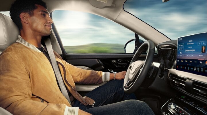 A person is shown using Lincoln BlueCruise hands-free highway driving technology on a divided highway called a Hands-Free Blue Zone. | Biondi Lincoln in Monroeville PA