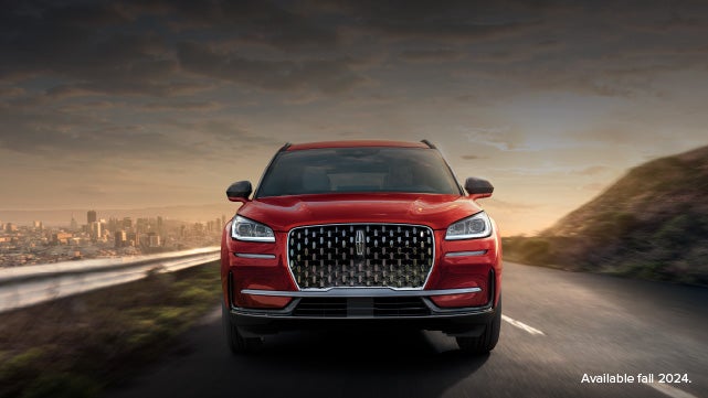 A 2025 red Lincoln Corsair® SUV is being driven down a road at sunset. | Biondi Lincoln in Monroeville PA