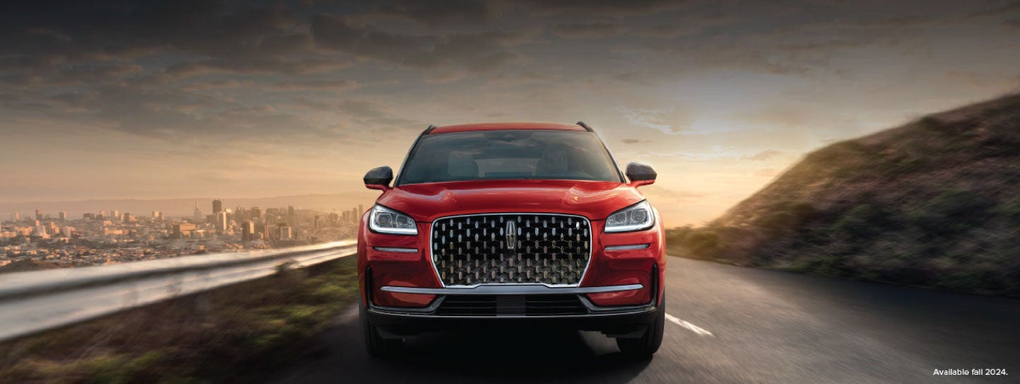 A 2025 red Lincoln Corsair® SUV is being driven down a road at sunset. | Biondi Lincoln in Monroeville PA