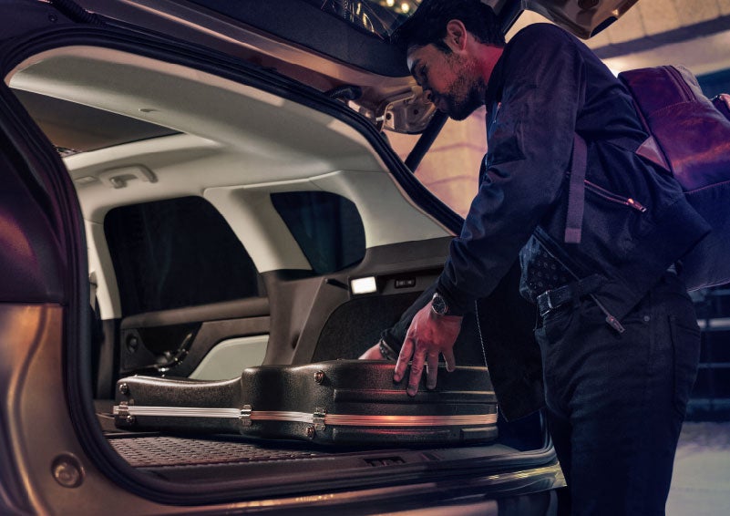A man is shown loading cargo into the rear of a 2024 Lincoln Corsair® SUV with the second-row seats folded flat. | Biondi Lincoln in Monroeville PA