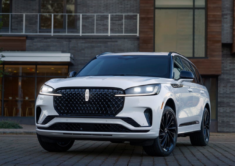 A 2026 Lincoln Aviator® Reserve model is shown with the available Jet Appearance Package parked near a restaurant. | Biondi Lincoln in Monroeville PA
