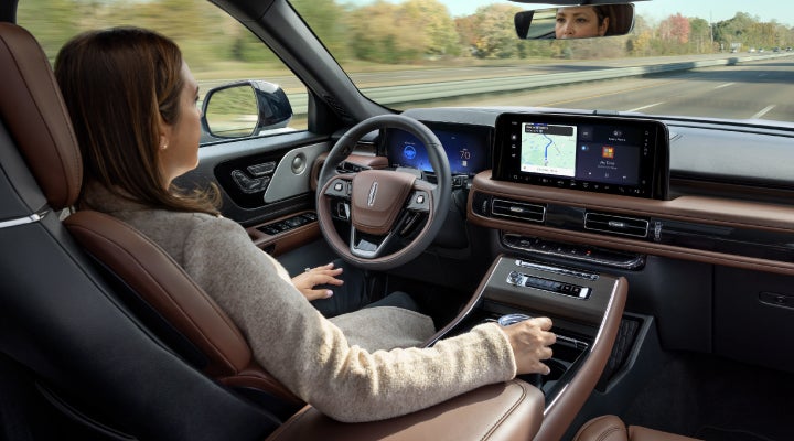 A 2026 Lincoln Aviator® SUV is being driven hands-free on a highway near a forest | Biondi Lincoln in Monroeville PA