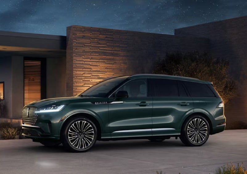 A green 2027 Lincoln Aviator® SUV is parked outside a contemporary home. | Biondi Lincoln in Monroeville PA