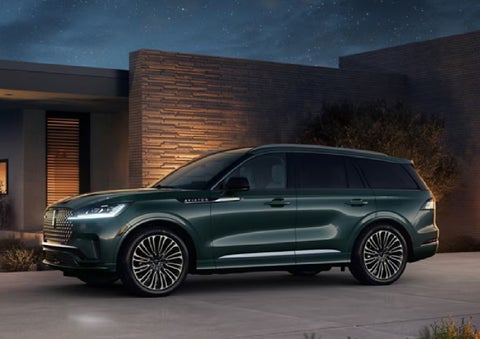 A green 2027 Lincoln Aviator® SUV is parked outside a contemporary home. | Biondi Lincoln in Monroeville PA