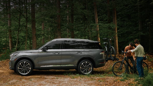 A father and son load e-bikes on a bike rack attached to a 2027 Lincoln Aviator® SUV. | Biondi Lincoln in Monroeville PA