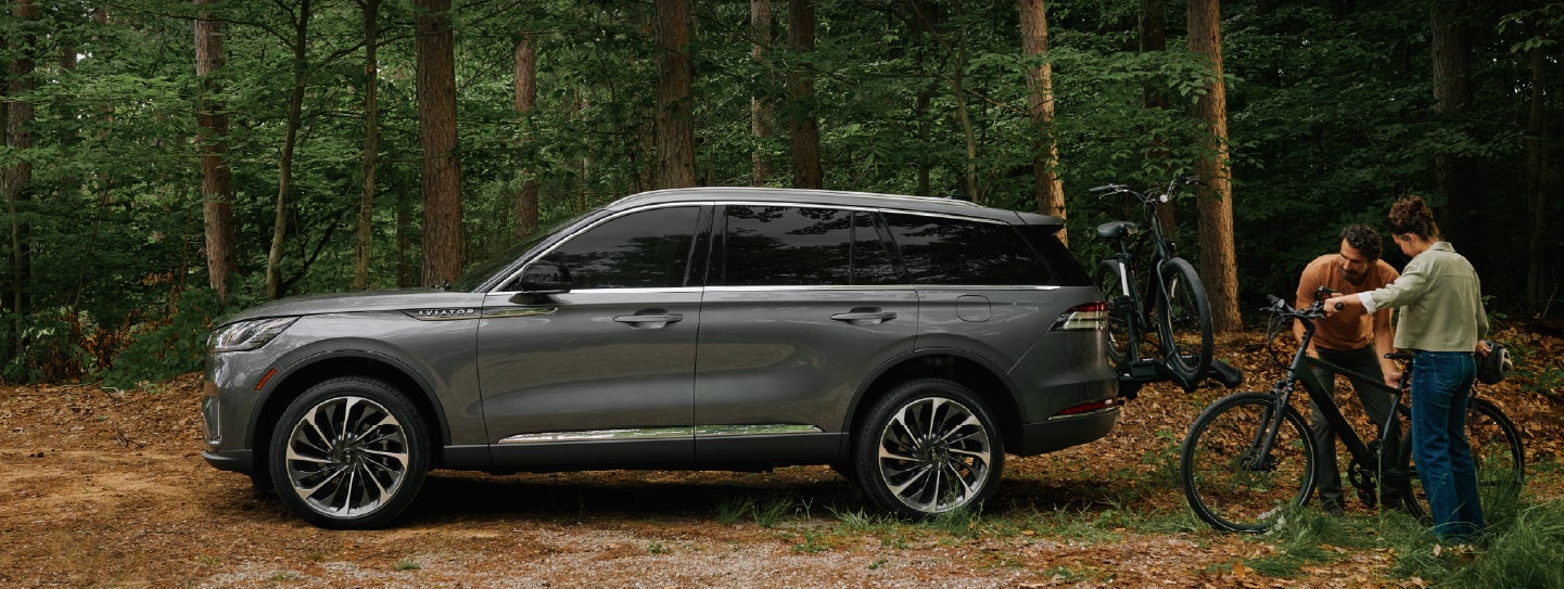 A father and son load e-bikes on a bike rack attached to a 2027 Lincoln Aviator® SUV. | Biondi Lincoln in Monroeville PA